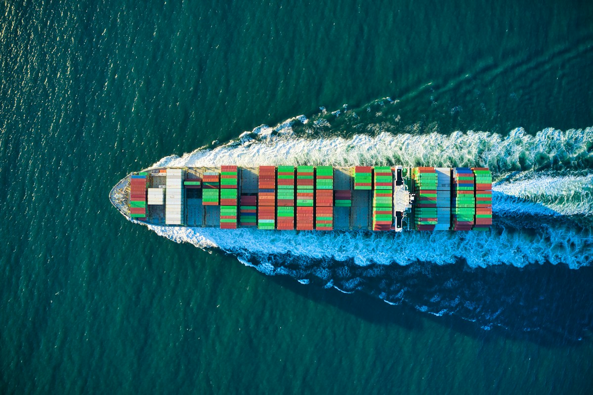 Aerial view of a cargo ship loaded with shipping containers, representing bulk used tire exports to the Autonomous Port of Conakry, Guinea.