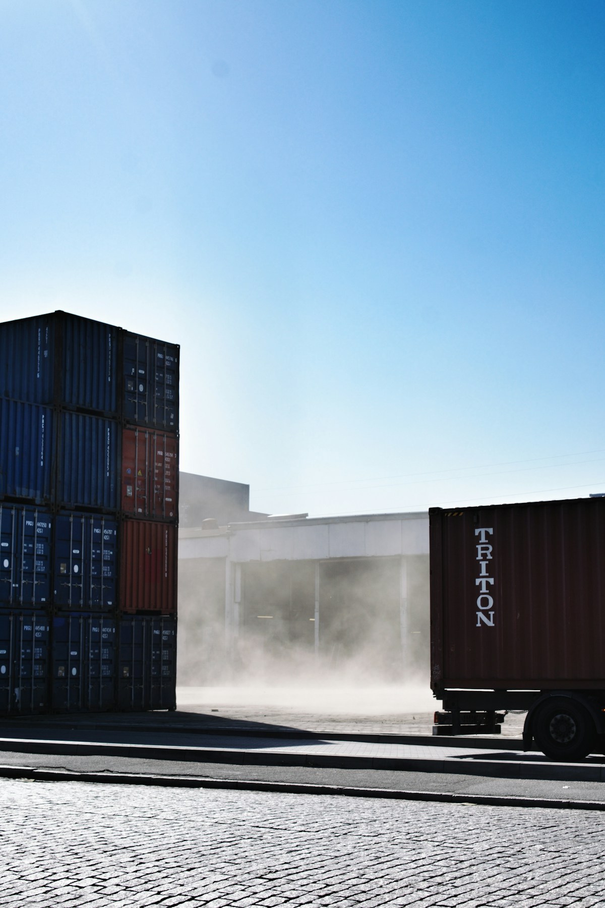 Shipping containers staged at a cargo port alongside a truck, representing container loads of used tires bound for the Freeport of Monrovia, Liberia.